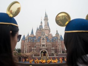 Women wearing Mickey Mouse ears watch the opening ceremony of the Shanghai Disney Resort in Shanghai on June 16, 2016.