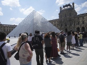 Tourists wait in line outside the Louvre museum which failed to open on time Monday, June 16, 2025 in Paris.