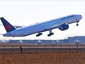 In this file photo, an Air Canada Boeing 777 takes off at the Calgary International Airport while WestJet Boeing 737 are lined up in storage in the distance on Tuesday, March 23, 2021.
