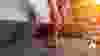 cropped shot of woman in rubber gloves cleaning sofa with vacuum cleaner