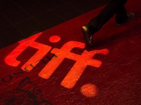 A man walks on a red carpet displaying a sign for the Toronto International Film Festival at the TIFF Bell Lightbox in Toronto.