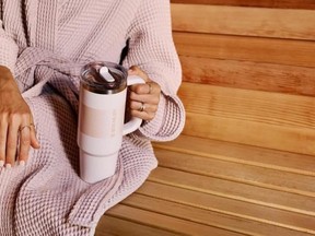 A hand holding a insulated tumbler by the handle.