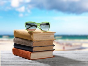 Books and sunglasses on beach background