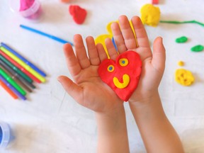 Child playing with plasticine, colorful modeling clay and sculpting heart . Home Education game with clay. Early development . Handmade concept for birthday, mothers day or valentines day