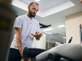 Personal trainer assisting sportswoman with her rehabilitation treatment at health club