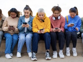 Panoramic image of multiracial group of teen college students ignoring each other looking at mobile phone checking social media. Gen z and technology concepts.