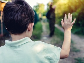 A young boy waves goodbye to their parent.