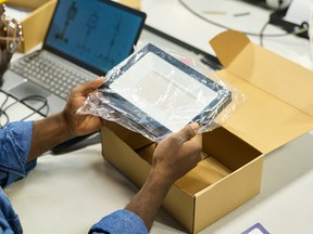 Hands of young male engineer holding new electric item in transparent packet before putting it in cardboard box