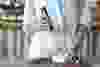 Mixing milk in glass pot by frother close up. Woman making foamy milk with handheld mixer. Housewife female iusing mixer whips cooking food in kitchen at home