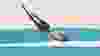 Contemporary art collage. Sportive young man diving into torn paper water isolated over pastel background with dust effect