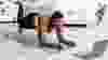 Plus size Afro woman working out at home with online personal trainer, using laptop, standing in elbow plank pose