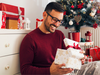 Smiling young man opening Christmas gift at home
