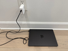 MacBook M4 in Space Black with the included black cord and white charging block.